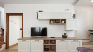 A modern kitchen with white cabinets, a built-in TV, and a wooden countertop. - 3287 Casa di Bea by Barbarhouse (Manduria)