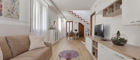 Ein modernes Wohnzimmer mit einer Couch, einem Glastisch und einem Fernseher.