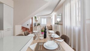 A modern dining area with a long table set for a meal, featuring a bottle of wine, multiple plates, and cutlery. - 3287 Casa di Bea by Barbarhouse (Manduria)