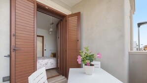 A balcony with a white table and chairs, a potted plant, and a wooden door. - 3287 Casa di Bea by Barbarhouse (Manduria)