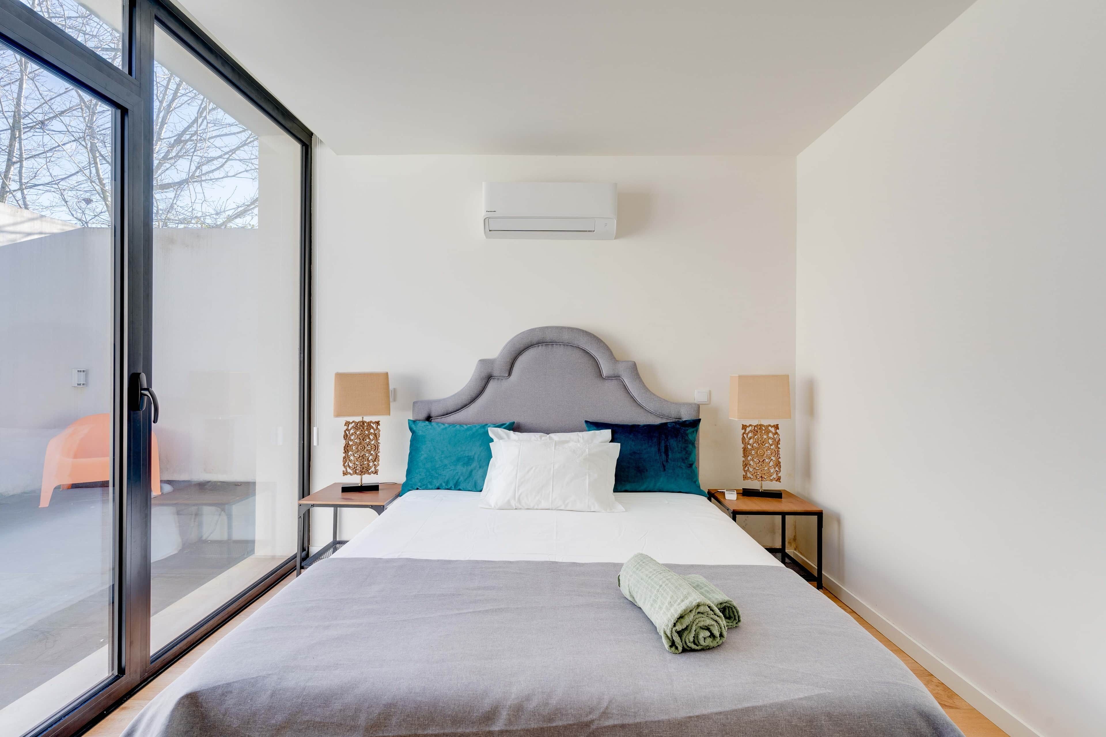 Una habitación de hotel con una cama grande, una ventana y un aire acondicionado instalado en la pared.