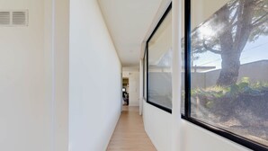 A narrow hallway with a wooden floor and large windows on one side.