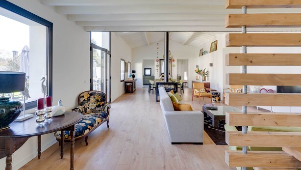 A spacious living area with a sofa, a dining table, and a kitchen in the background.