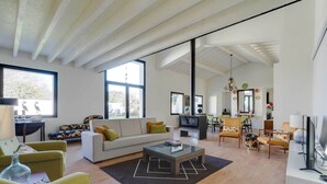 A spacious living room with a sofa, chairs, a coffee table, and a television.
