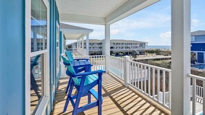 Un balcon avec vue sur un immeuble et une plage.