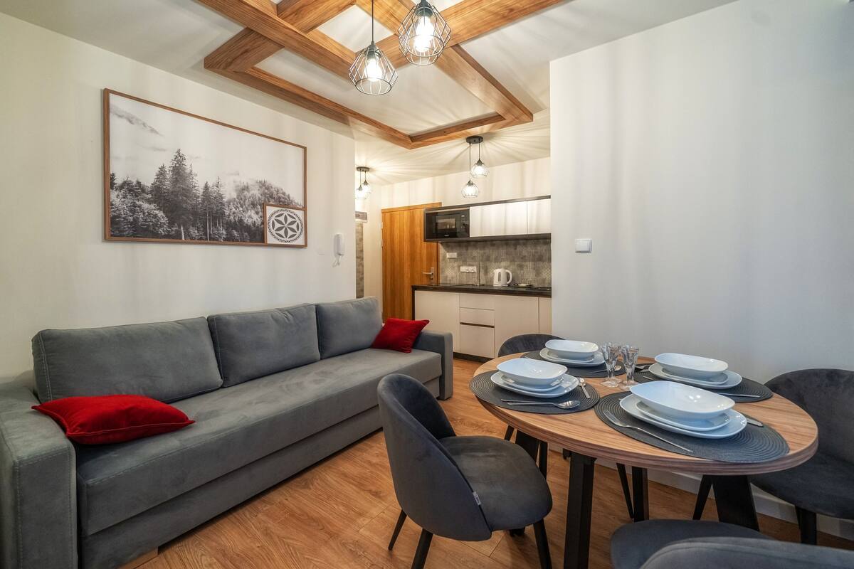 Un espace de vie compact comprenant un canapé, une table à manger, des chaises et un coin cuisine.