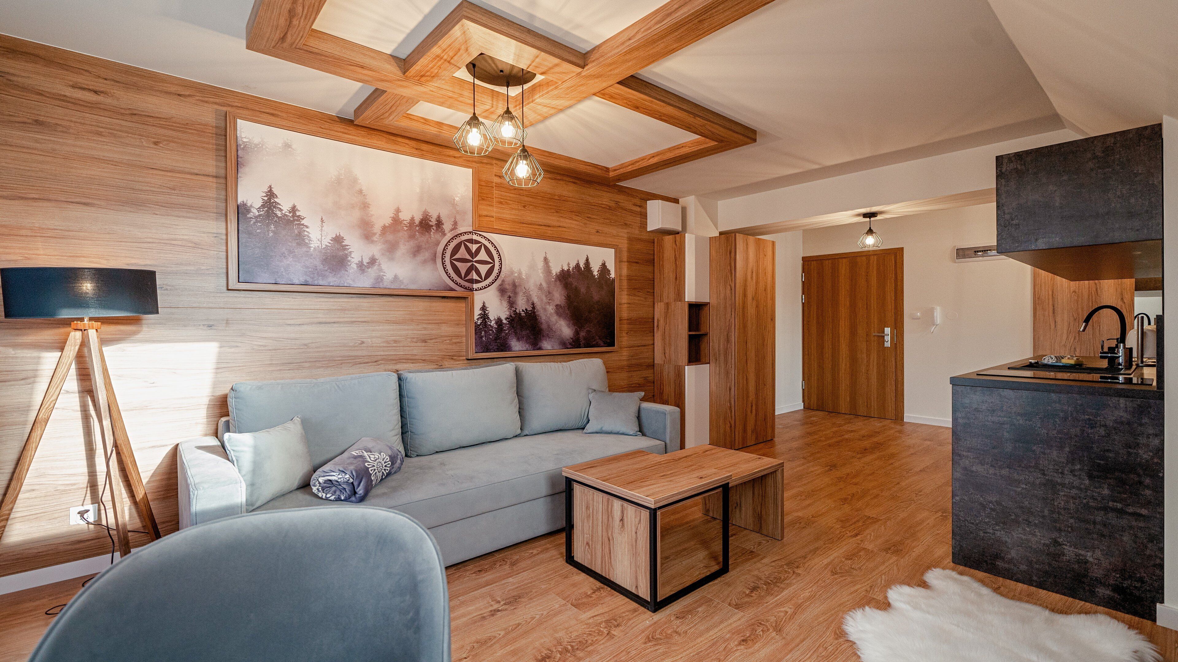 A modern living room with a wooden ceiling, a sofa, a coffee table, and a painting of a forest.