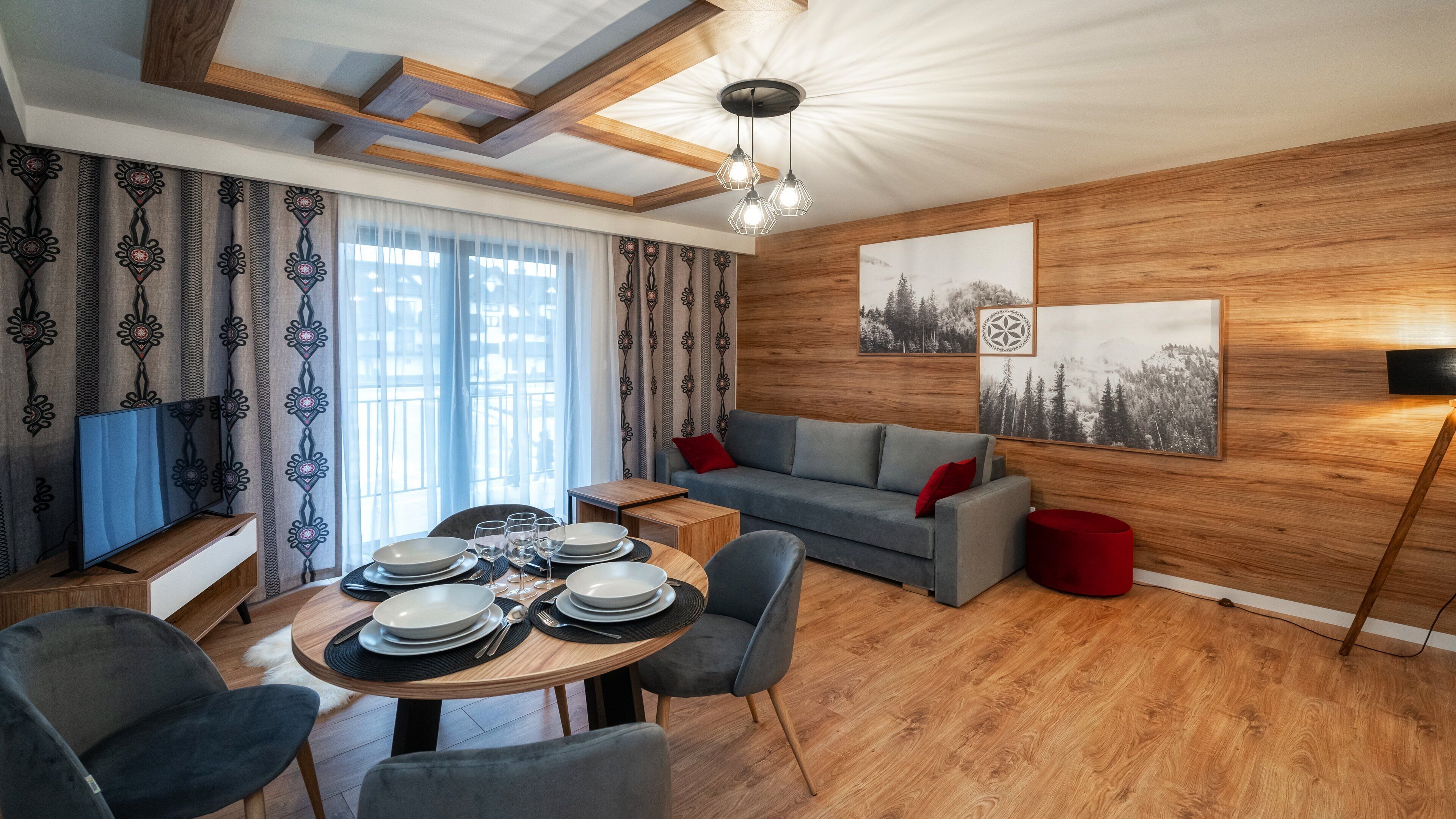 Een moderne woonkamer met een eethoek, houten wanden en een groot raam met gordijnen.