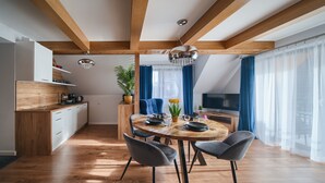 Una cocina moderna con armarios de madera, un comedor con mesa redonda y un televisor fijado en la pared.