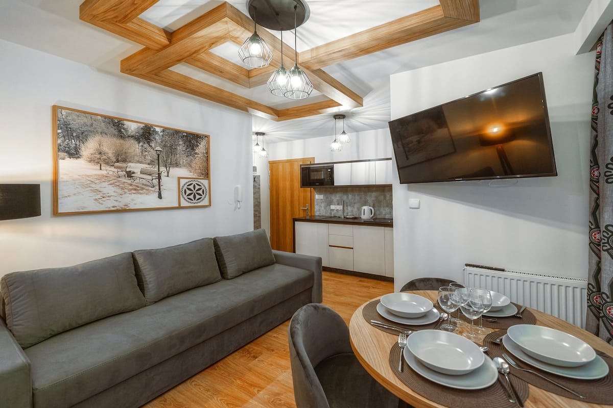 Un salon moderne avec un canapé, une table à manger pour quatre personnes et une cuisine en arrière-plan.