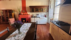 A cozy kitchen with wooden cabinets, a red fireplace, and a dining area with a table set for two. - Tango House (Zandobbio)