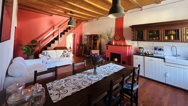 A cozy living room with a fireplace, wooden ceiling, and a dining area with a table set for four. - Tango House (Zandobbio)
