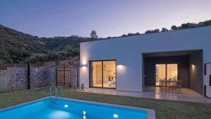 A modern house with a swimming pool, large glass doors, and a stone wall. - Deluxe Villa Christos (Malevizi)