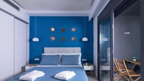 A modern bedroom with a blue wall, a white bed, and decorative wall mirrors. - Deluxe Villa Christos (Malevizi)