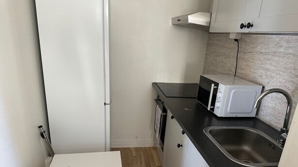 A compact kitchen with a microwave, sink, and small table. - Apartment in Kista, Stockholm (Kista)