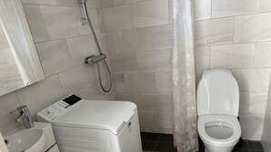 A bathroom with a washing machine, a toilet, and a sink. - Apartment in Kista, Stockholm (Kista)
