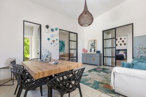 A modern living room with a wooden dining table, black chairs, a hanging light fixture, and a sofa. - 3284 Villa Anita by Barbarhouse (Manduria)