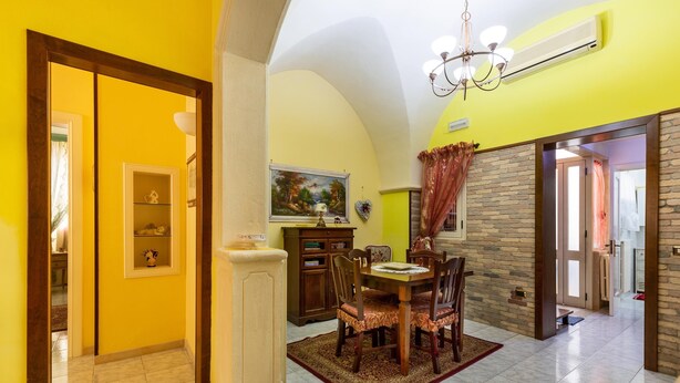A dining area with a table and chairs, a chandelier, and a painting on the wall. - 3283 Appartamento Garibaldi by Barbarhouse (Carmiano)