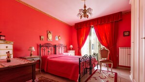 A bedroom with a red theme, including a bed, a chair, a desk, and a nightstand. - 3283 Appartamento Garibaldi by Barbarhouse (Carmiano)