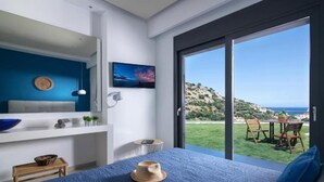 A bedroom with a large bed, a TV, a window with a view of the sea, and a balcony with outdoor furniture. - Deluxe Villa Konstantinos (Malevizi)