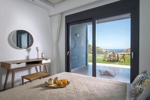 Ein Schlafzimmer mit Bett, Nachttisch, Spiegel und Blick auf einen Balkon mit Tisch und Stühlen.