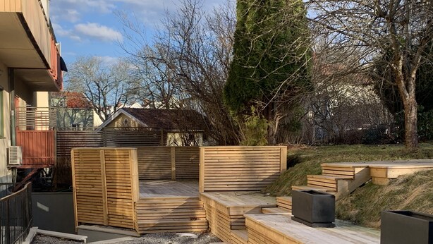 Eine Holzterrasse mit integriertem Sitzbereich und einem Feuerkorb.