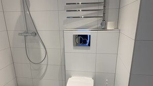Ein modernes Badezimmer mit Toilette, Duschbrause und Toilettenbürste.
