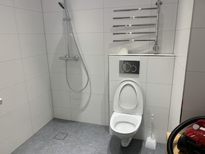 Uma casa de banho moderna com sanita, chuveiro e secador de mãos.