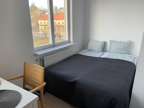 Et soveværelse med seng, stol, et vindue og en radiator.