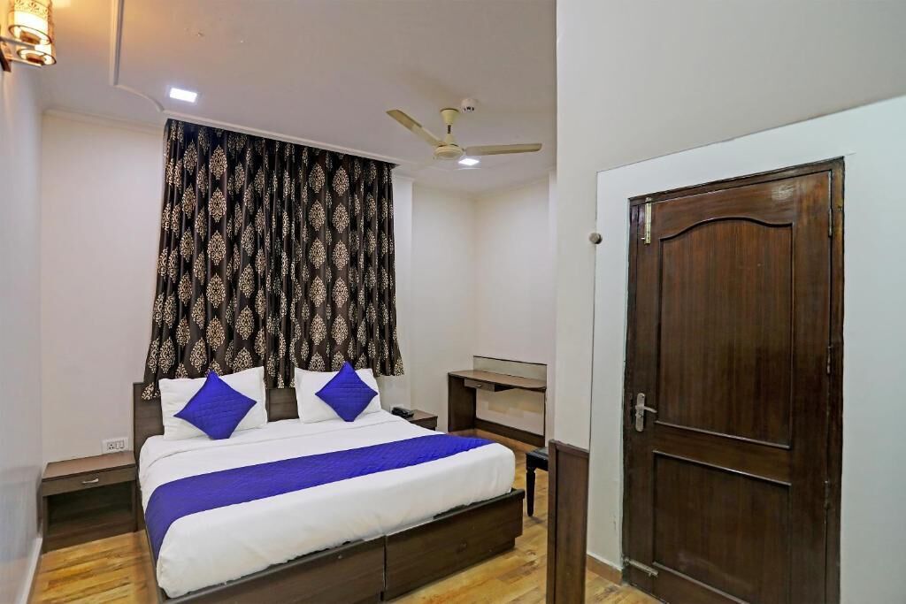 Une chambre à coucher avec un lit, un ventilateur de plafond, une porte en bois et un rideau à motifs.