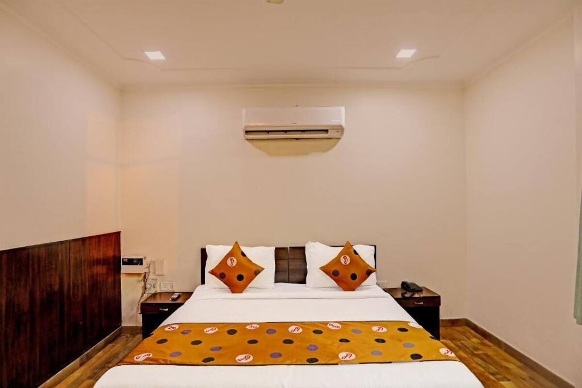A hotel room with a bed, a nightstand, an air conditioning unit, and a wooden headboard.