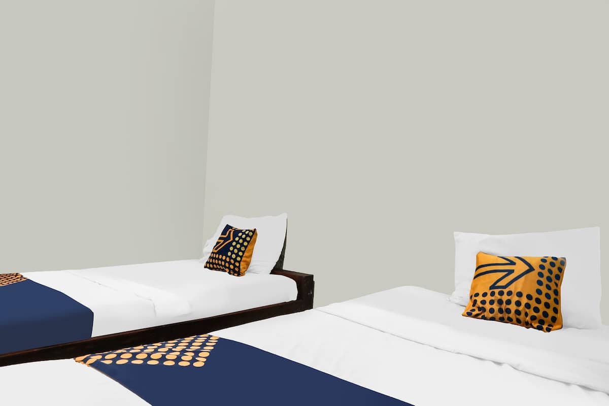 Two single beds with white bedding and blue and yellow patterned bedspreads.
