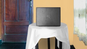 A laptop on a white table in a room with a wooden door and a yellow wall. - SPOT ON 92063 Balebat Endah Syariah (Pangandaran)