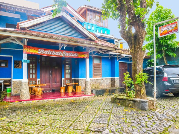 A building with a blue facade, a red entrance, and a signboard.