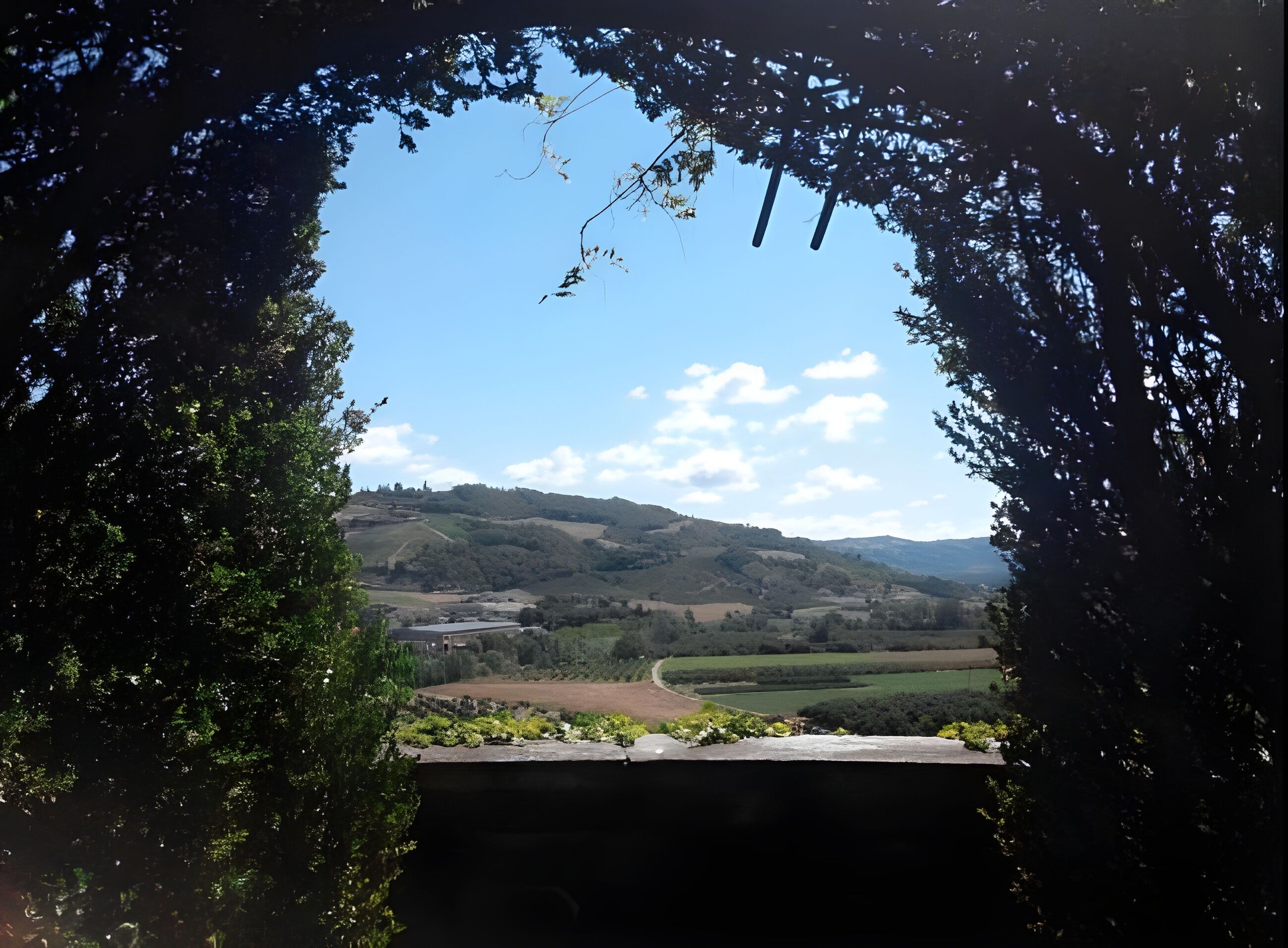 A view through an archway of a valley with hills and a clear sky.