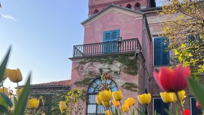 A pink building with a balcony and a window with a metal frame. - Il Castello di Bubbio (Bubbio)