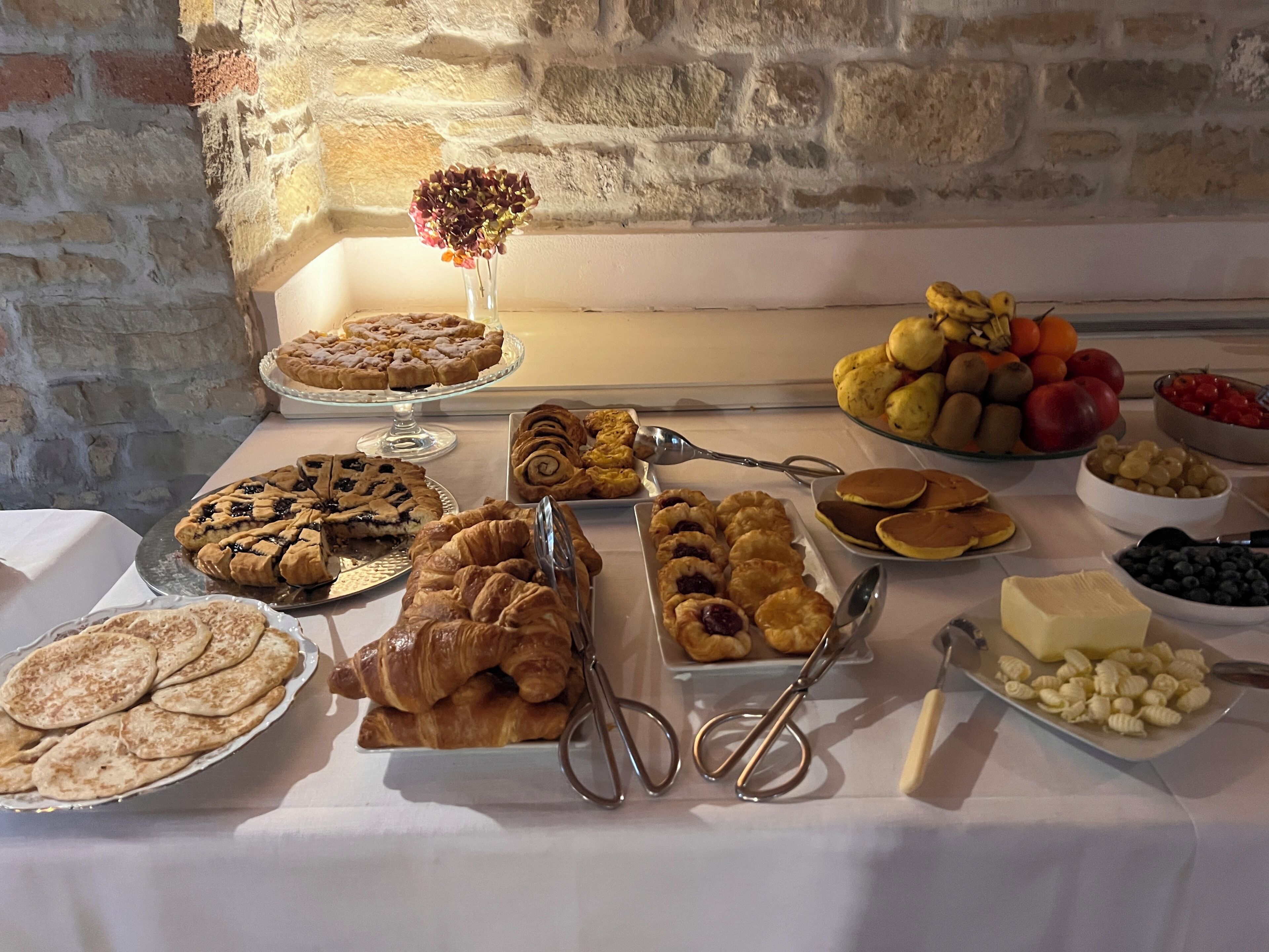 A breakfast buffet with various pastries, fruits, and condiments.