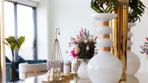 A modern living room with a glass coffee table, white and gold vases, and a decorative plant. - Dream Residence (Al Khobar)