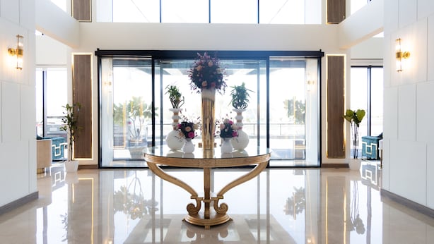 A spacious lobby with a central decorative table, large windows, and potted plants. - Dream Residence (Al Khobar)