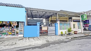 Fachada con revestimiento azul, una puerta metálica y un cartel.