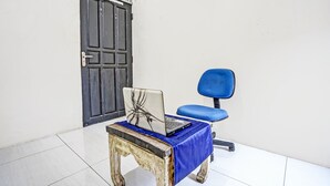Una habitación con una mesa de madera, una silla azul y un ordenador portátil sobre la mesa.