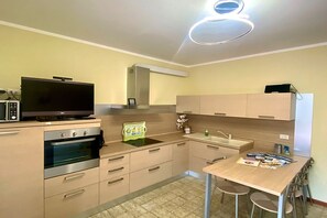 A modern kitchen with a built-in oven, a microwave, a sink, and a dining area with a table and chairs.