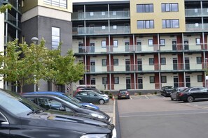 Ein mehrstöckiges Wohnhaus mit Balkonen, einem Parkplatz und mehreren parkenden Autos.
