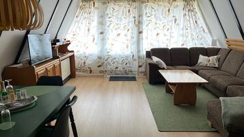 A cozy living room with a sofa, a coffee table, and a TV on a wooden cabinet.