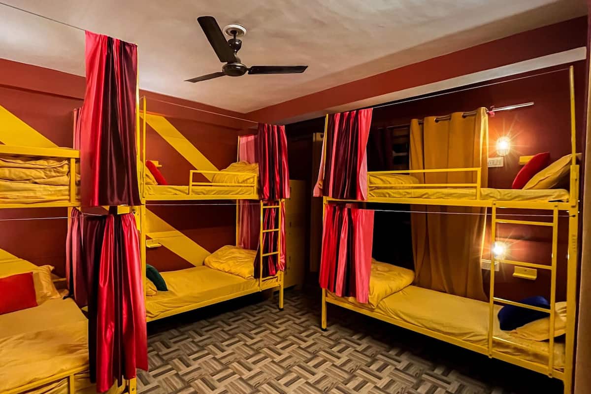 A dormitory room with bunk beds, a ceiling fan, and patterned flooring.