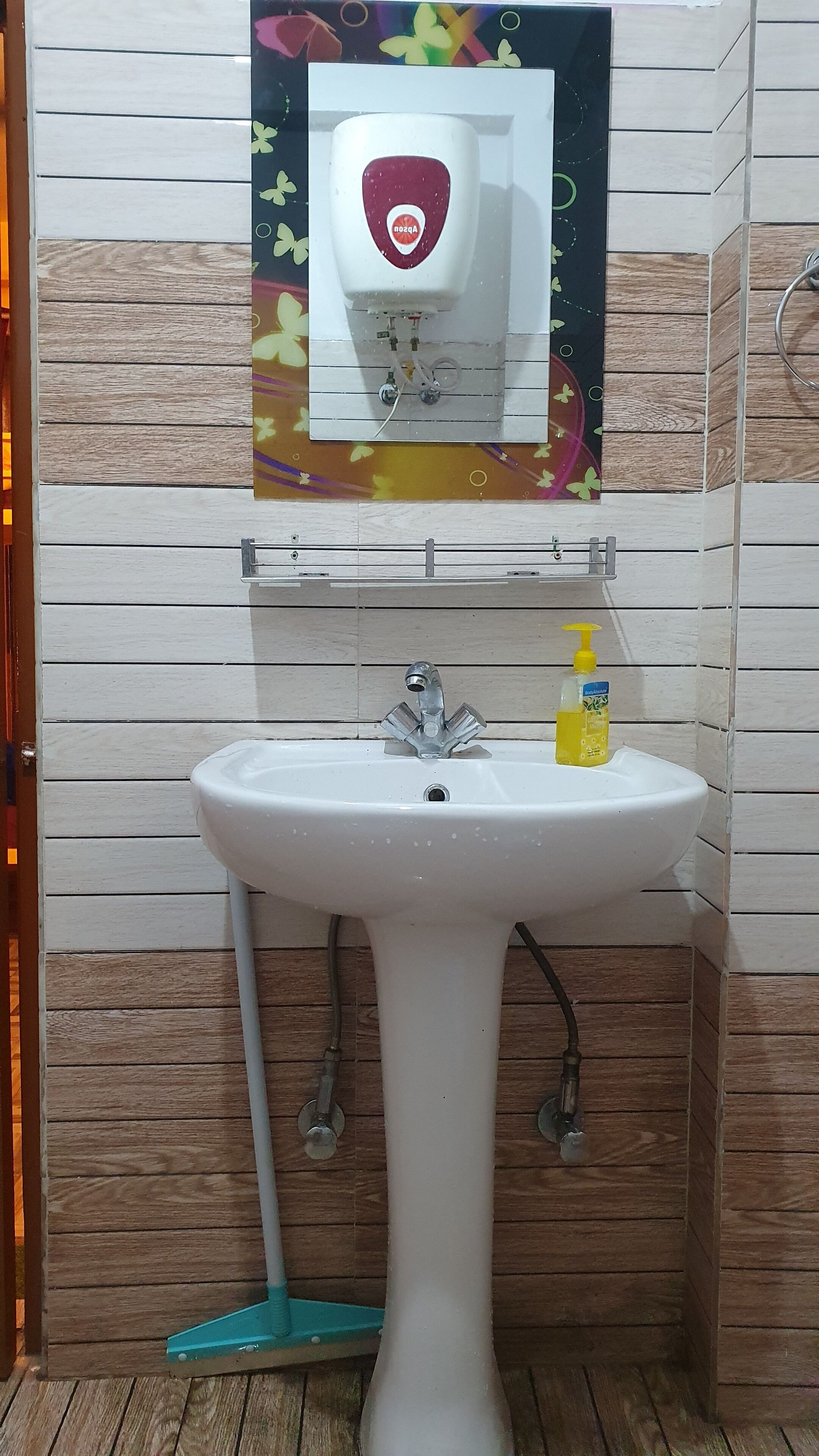 Une salle de bain avec un lavabo blanc, un miroir au-dessus et un distributeur de savon sur la droite.