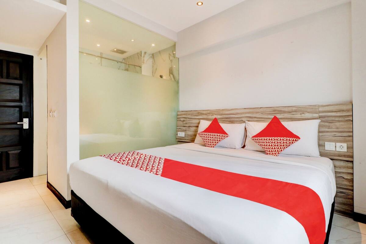 Een moderne hotelkamer met een groot bed, een douchecabine van glas en een houten hoofdeinde.