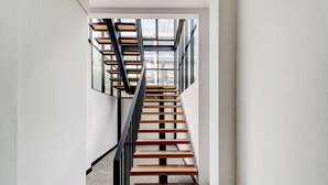 A modern staircase with wooden steps and black railings, leading to a room with large windows. - Collection O Cihampelas Near Ciwalk Formerly I Sleep Hotel (Bandung)