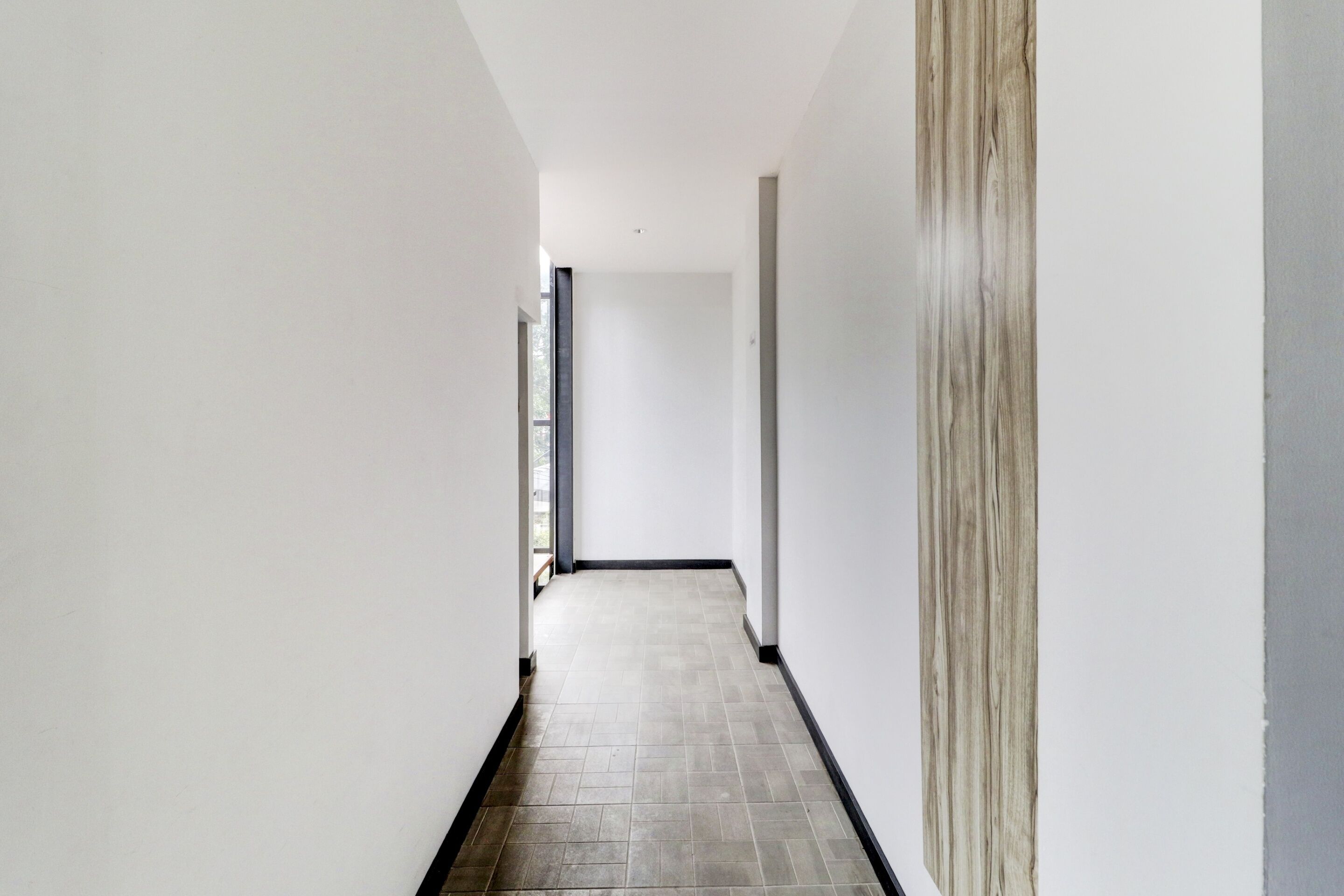 A narrow, well-lit hallway with a tiled floor and white walls.
