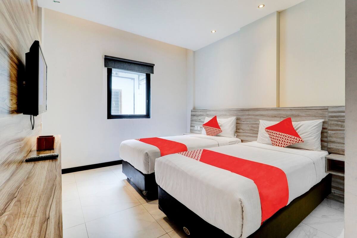 Een hotelkamer met twee bedden, een televisie, een raam en een houten accentmuur.